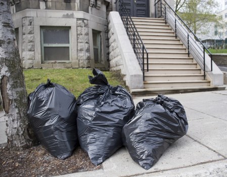 Workers using protective equipment and lifting aids during rubbish removal